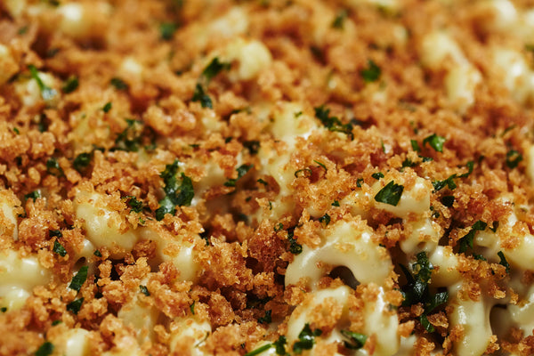 Close up image of vegan mac and cheese covered in toasted breadcrumbs with chopped parsley
